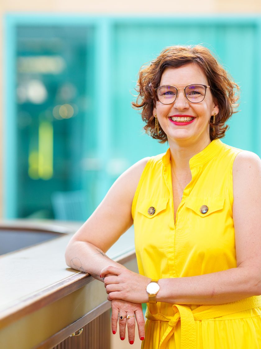 Nadine Grigoleit, Organisationsentwicklungs-Spezialistin, anlehend an ein Geländer und in die Kamera lächelnd