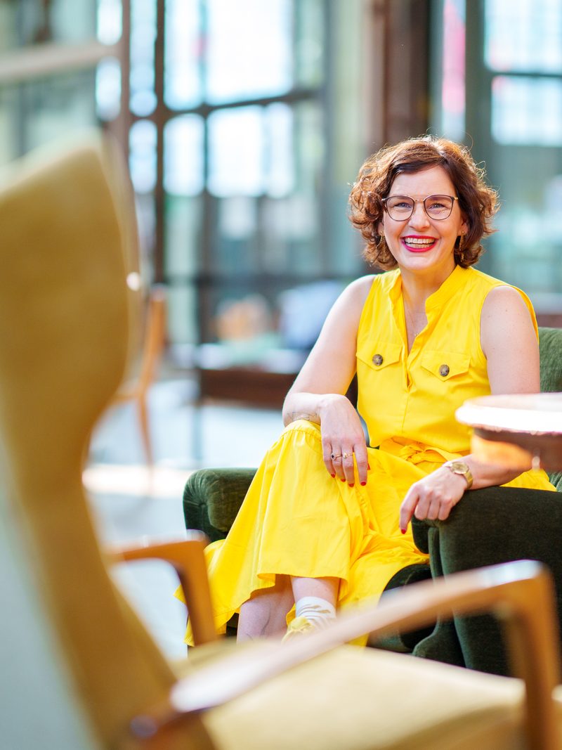 Nadine Grigoleit sitzt entspannt in einem grünen Sessel und lächelt